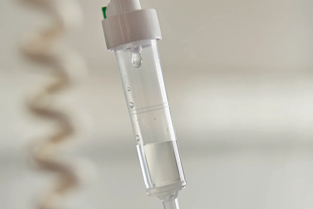 Close-up of an IV drip chamber with a single droplet forming